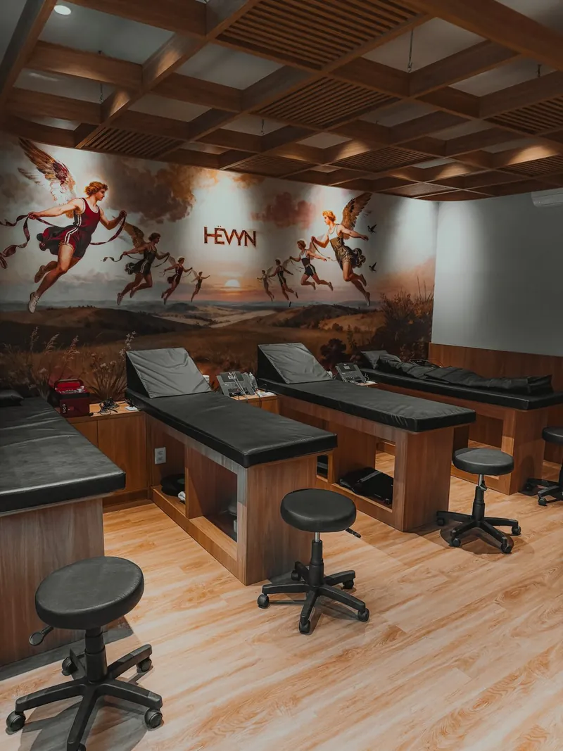 Sala de fisioterapia com macas e o mural HËVYN