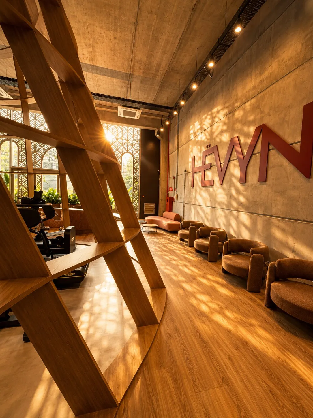 Lounge da HËVYN com poltronas e o letreiro na parede de concreto