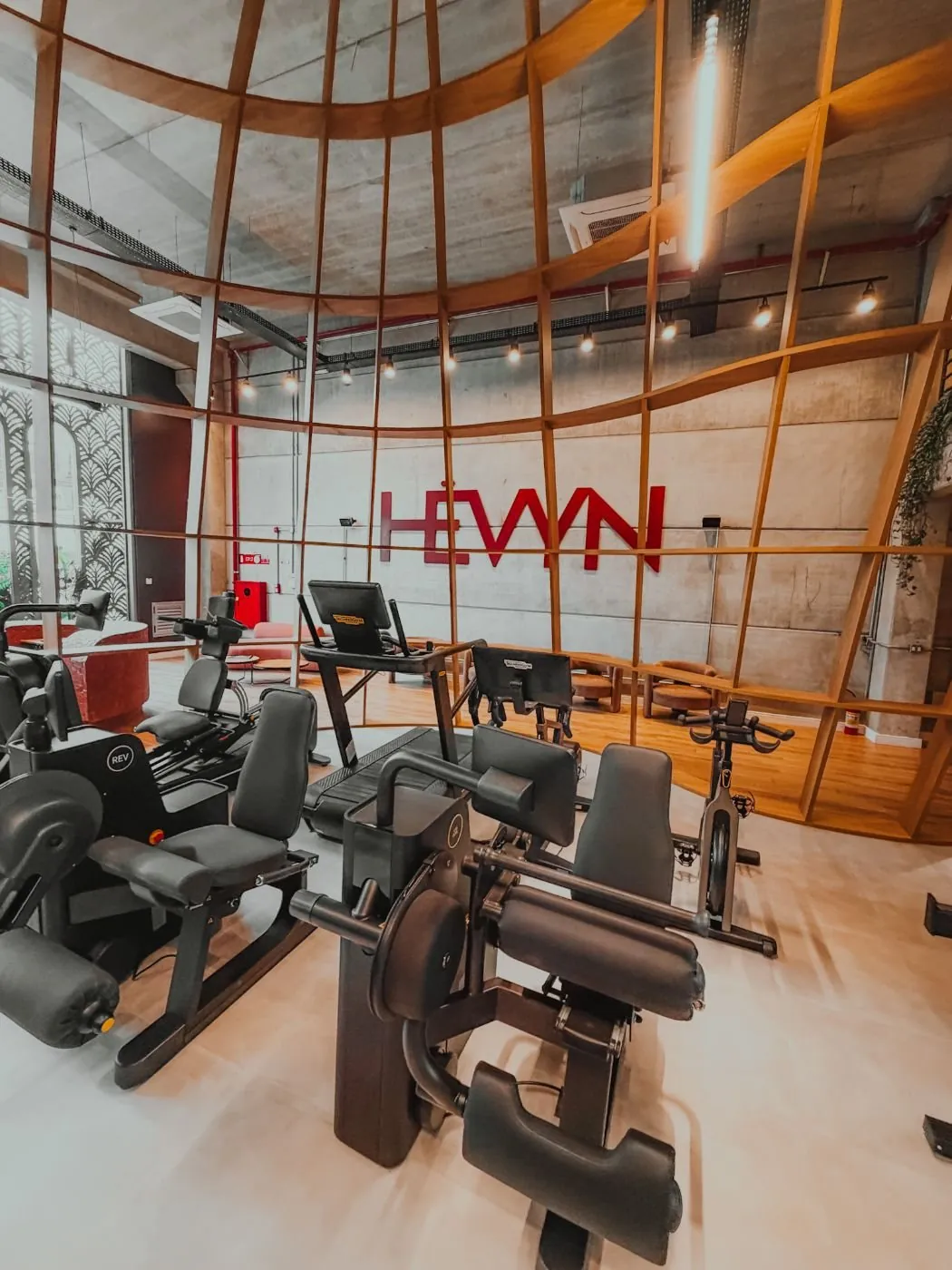 Sala de fortalecimento com equipamentos Technogym sob a estrutura de madeira